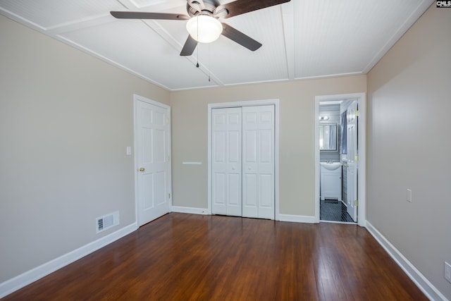 unfurnished bedroom with ornamental molding, ensuite bath, a closet, dark wood-type flooring, and ceiling fan