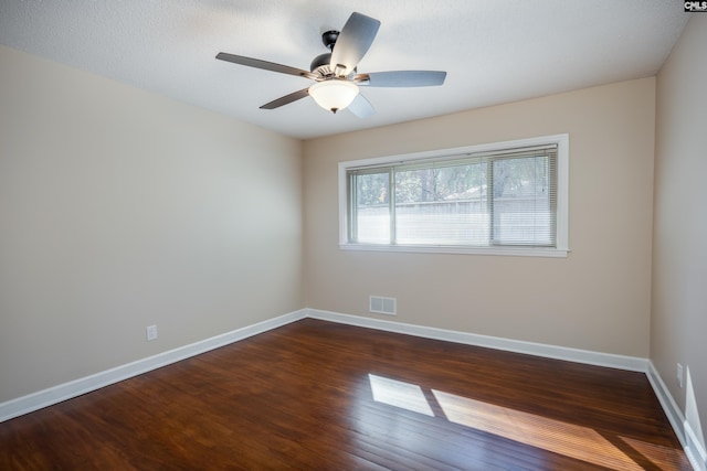 empty room featuring a textured ceiling, ceiling fan, and dark wood-type flooring