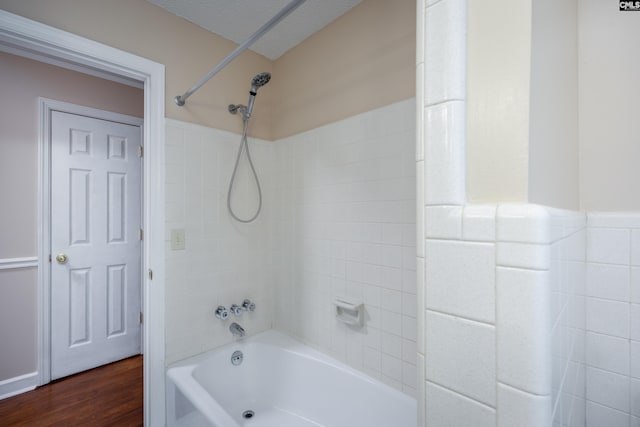 bathroom featuring a textured ceiling, hardwood / wood-style floors, and tiled shower / bath combo