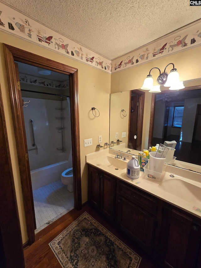 full bathroom featuring hardwood / wood-style floors, a textured ceiling, toilet, vanity, and shower / bathtub combination