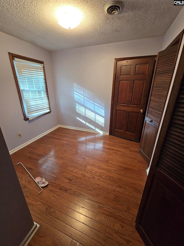 unfurnished room with hardwood / wood-style floors and a textured ceiling