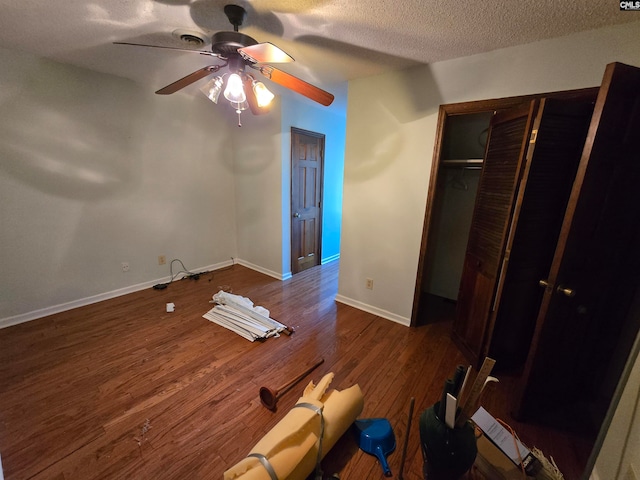 unfurnished bedroom with ceiling fan, dark hardwood / wood-style flooring, a textured ceiling, and a closet