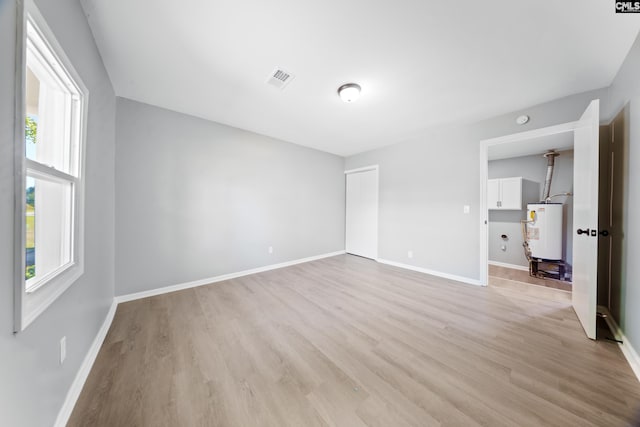 empty room featuring plenty of natural light, gas water heater, and light hardwood / wood-style flooring