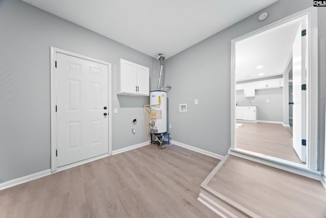 laundry room with cabinets, light hardwood / wood-style floors, and water heater