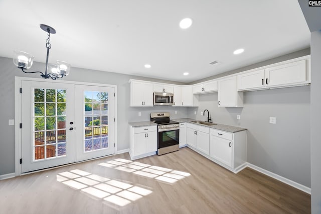 kitchen with sink, white cabinetry, hanging light fixtures, and appliances with stainless steel finishes