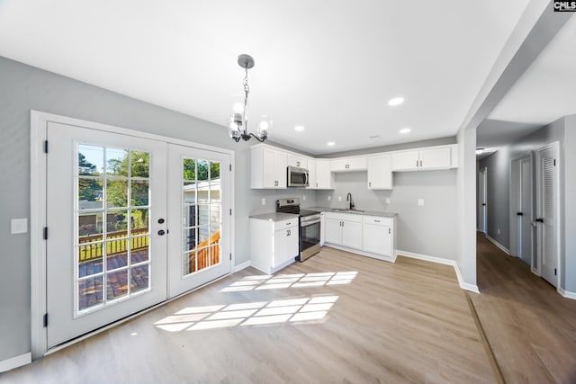 kitchen with pendant lighting, french doors, light wood-type flooring, appliances with stainless steel finishes, and white cabinetry