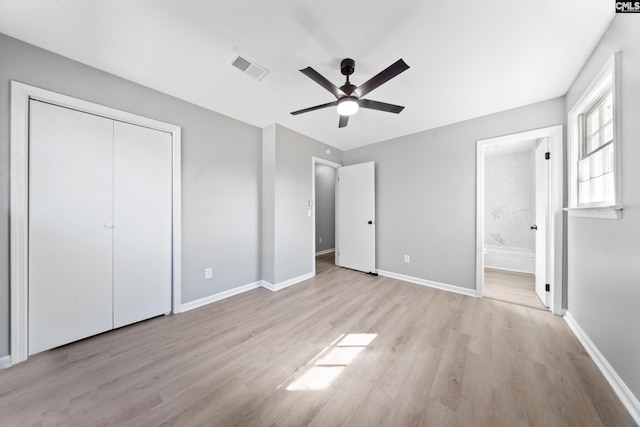 unfurnished bedroom with ceiling fan, ensuite bath, light wood-type flooring, and a closet