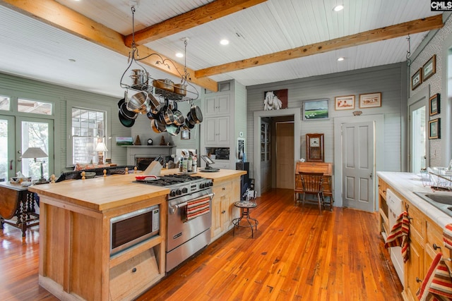 kitchen with butcher block counters, a center island, stainless steel appliances, beamed ceiling, and light wood-type flooring