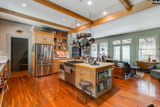 kitchen featuring wooden counters, appliances with stainless steel finishes, dark wood-type flooring, and beam ceiling