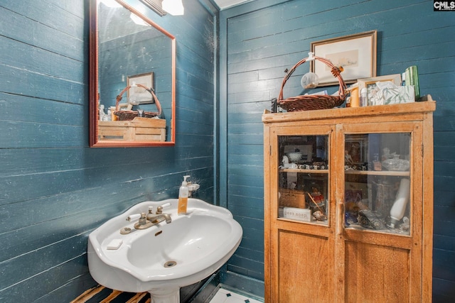 bathroom featuring wooden walls and sink