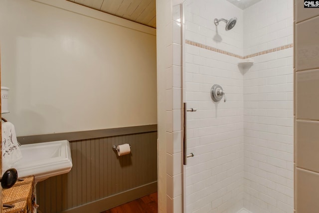 bathroom with hardwood / wood-style flooring, a shower with shower door, and wooden walls