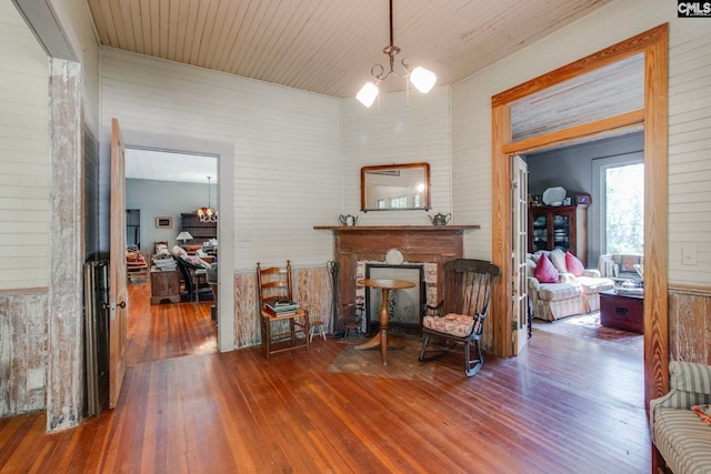 living area featuring a notable chandelier, wooden walls, a fireplace, wood ceiling, and hardwood / wood-style flooring