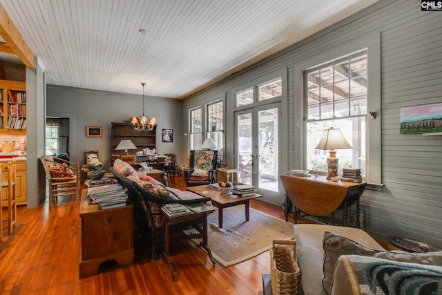 living room with a chandelier, french doors, wood-type flooring, and wooden walls