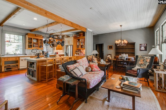 living room featuring hardwood / wood-style floors, beamed ceiling, and an inviting chandelier