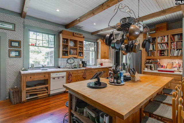 kitchen featuring dishwasher, stainless steel fridge, light wood-type flooring, and beamed ceiling