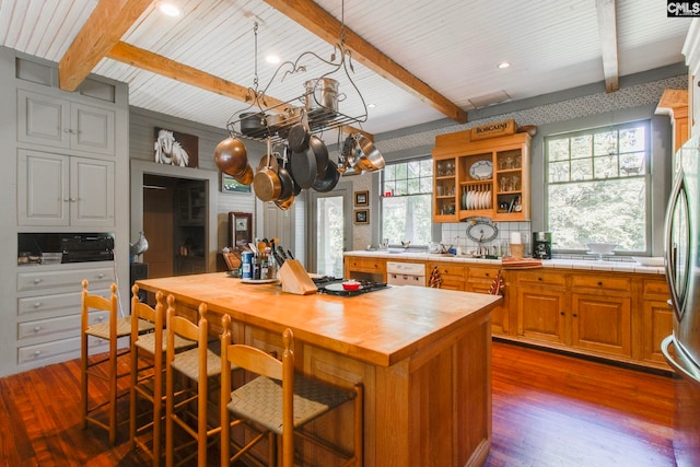 kitchen featuring beamed ceiling, a center island, and plenty of natural light