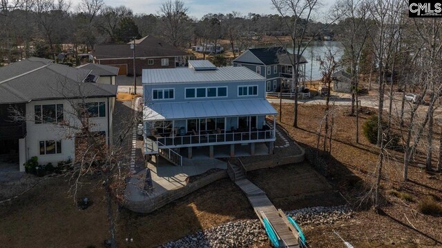 rear view of house featuring solar panels and a water view