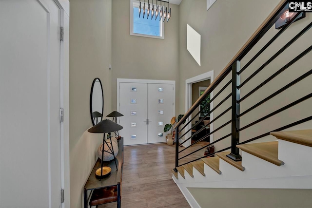 entryway with hardwood / wood-style floors and a towering ceiling