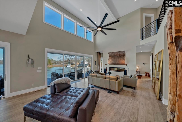 living room featuring ceiling fan, light wood-type flooring, and a towering ceiling