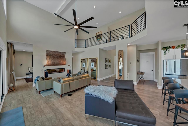 living room with a high ceiling, light hardwood / wood-style flooring, and ceiling fan