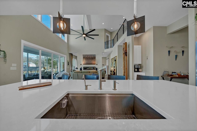 kitchen with ceiling fan, sink, and a high ceiling