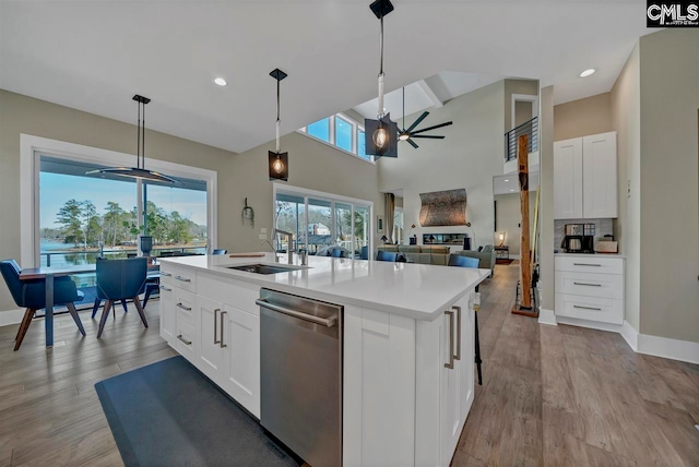 kitchen featuring pendant lighting, a center island with sink, stainless steel dishwasher, ceiling fan, and white cabinetry