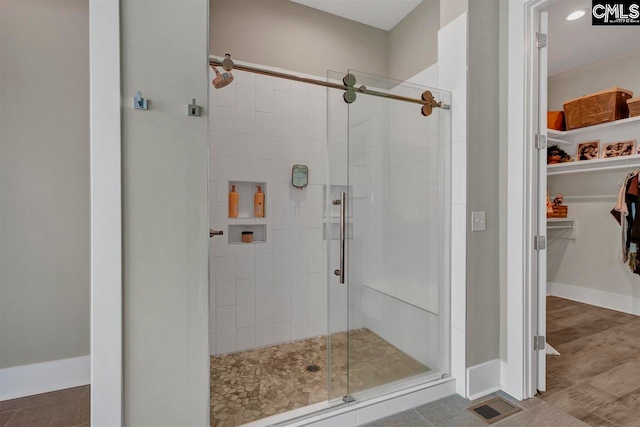 bathroom with a shower with shower door and hardwood / wood-style flooring