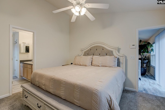 carpeted bedroom with ceiling fan, ensuite bathroom, and vaulted ceiling