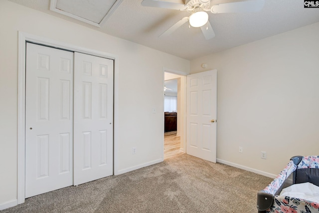 unfurnished bedroom featuring ceiling fan, a closet, light colored carpet, and a textured ceiling