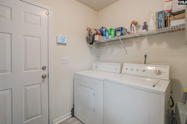 washroom with light wood-type flooring, a textured ceiling, and washing machine and clothes dryer