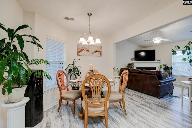 dining room featuring ceiling fan with notable chandelier and light hardwood / wood-style floors