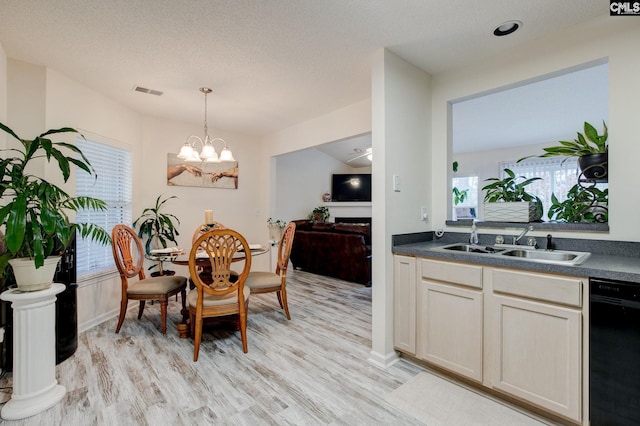 dining space featuring a textured ceiling, light hardwood / wood-style flooring, an inviting chandelier, and sink