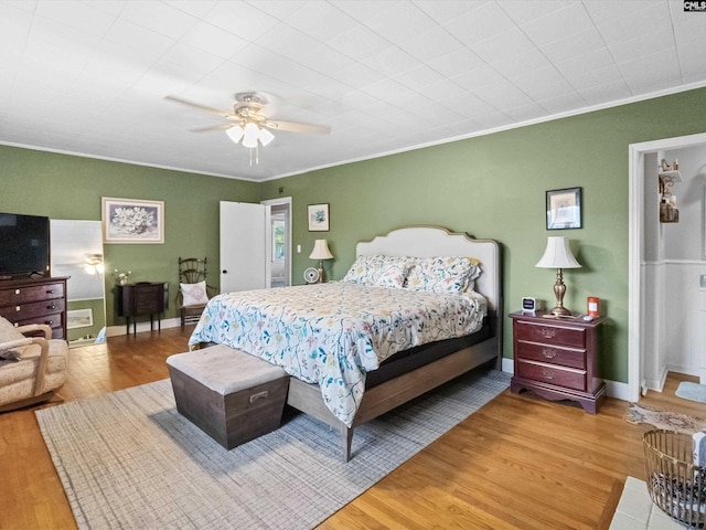 bedroom featuring hardwood / wood-style floors, ceiling fan, and crown molding