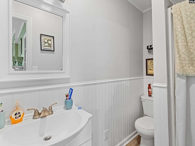 bathroom with toilet, ornamental molding, and sink