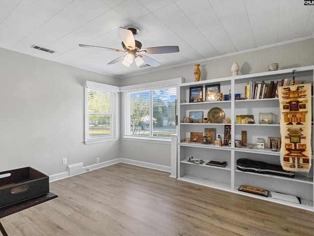 interior space with wood-type flooring, ceiling fan, and ornamental molding