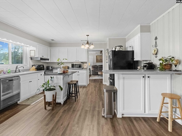 kitchen with dark wood-type flooring, stainless steel appliances, a kitchen breakfast bar, crown molding, and white cabinets