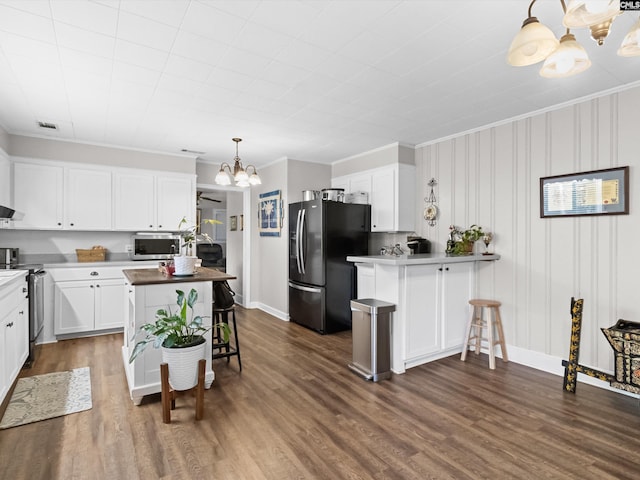 kitchen with white cabinets, decorative light fixtures, dark hardwood / wood-style floors, and appliances with stainless steel finishes