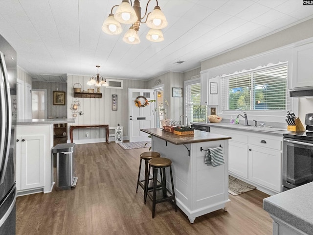 kitchen featuring hardwood / wood-style floors, white cabinetry, hanging light fixtures, and appliances with stainless steel finishes