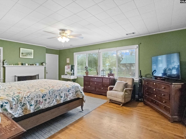 bedroom with light wood-type flooring, ceiling fan, and crown molding