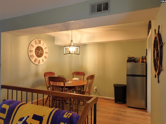 dining room featuring light wood-type flooring and an inviting chandelier