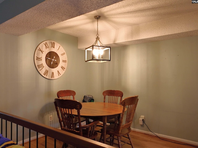 dining space with wood-type flooring, a textured ceiling, and a notable chandelier