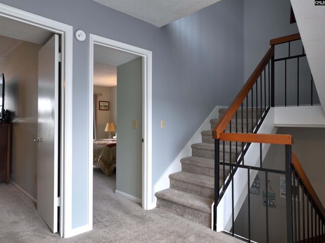 stairs featuring carpet and a textured ceiling