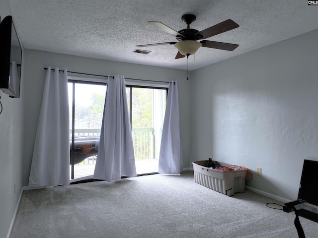 carpeted empty room with ceiling fan and a textured ceiling