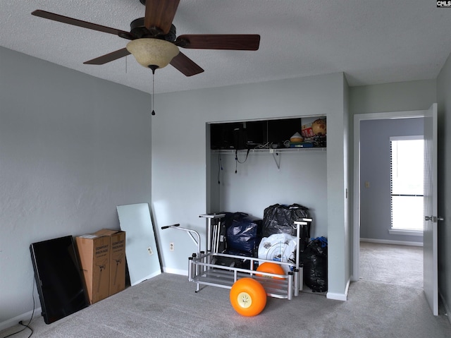 carpeted bedroom with ceiling fan, a closet, and a textured ceiling