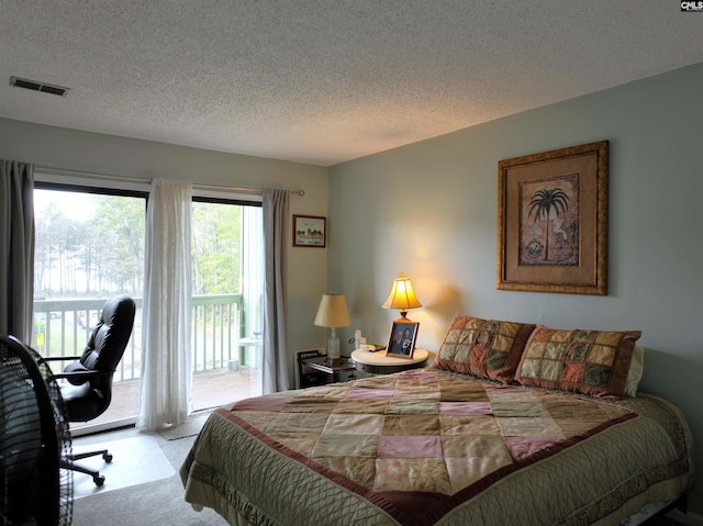 bedroom with access to exterior, a textured ceiling, and light carpet