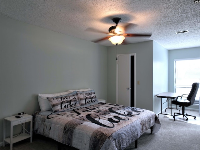 carpeted bedroom with ceiling fan and a textured ceiling