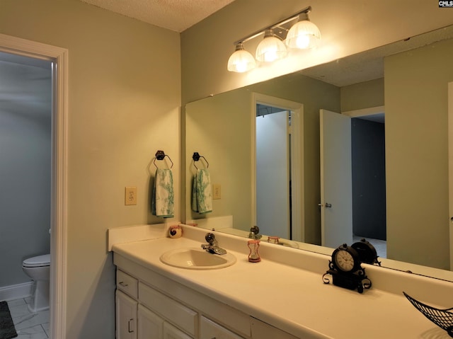 bathroom featuring vanity, a textured ceiling, and toilet