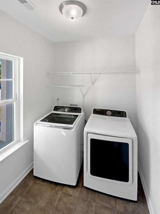 washroom featuring washing machine and dryer and dark tile patterned flooring