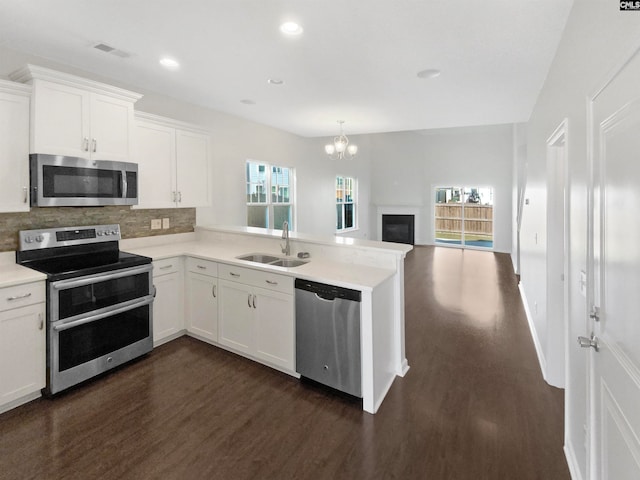 kitchen featuring kitchen peninsula, stainless steel appliances, white cabinetry, and sink