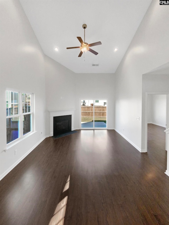 unfurnished living room with dark hardwood / wood-style flooring, plenty of natural light, and high vaulted ceiling